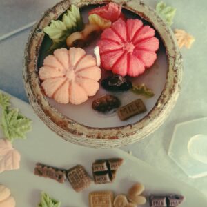 Vela artesanal de cera natural decorada con figuritas otoñales de cera: calabazas, hojas y dulces elaborados en el taller de velas naturales de La Caléndula.