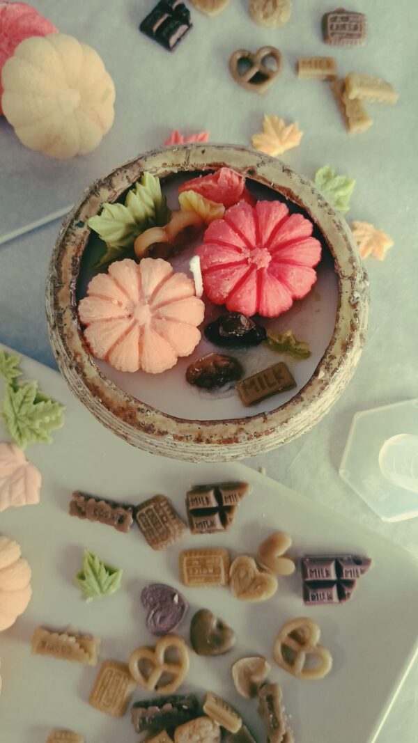 Vela artesanal de cera natural decorada con figuritas otoñales de cera: calabazas, hojas y dulces elaborados en el taller de velas naturales de La Caléndula.